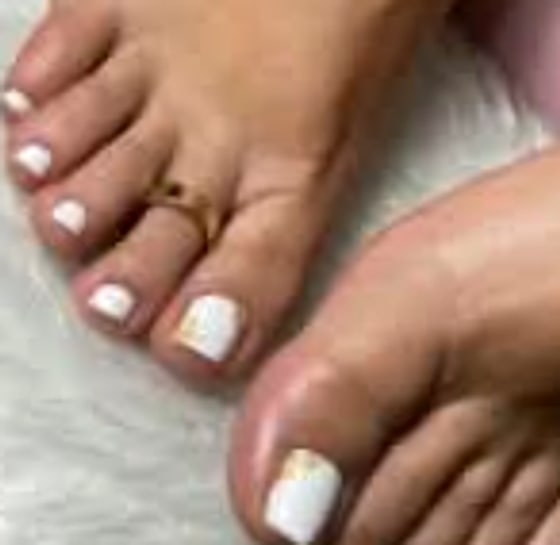 Pedicura con esmaltado blanco y detalle dorado